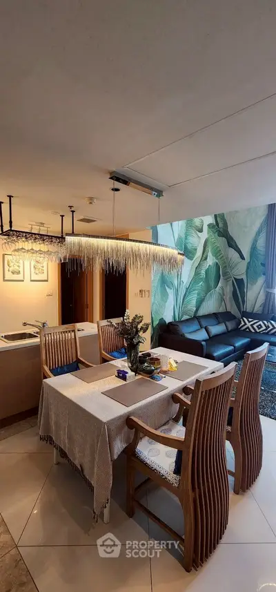 Stylish dining area with wooden chairs and tropical wall design in modern apartment.