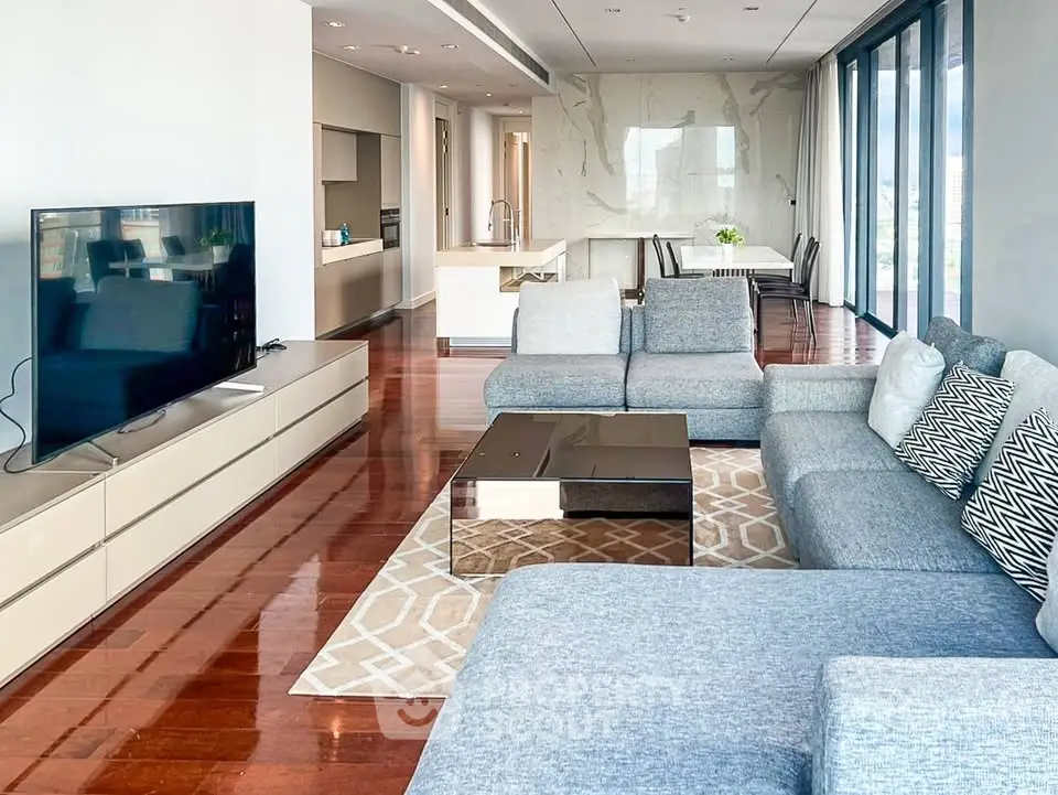 Spacious modern living room with sleek design and open kitchen layout, featuring large windows and elegant furnishings.