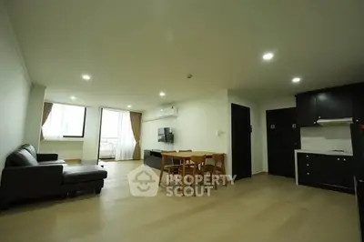 Spacious open-plan living room with modern kitchen and dining area, featuring natural light and stylish furnishings.