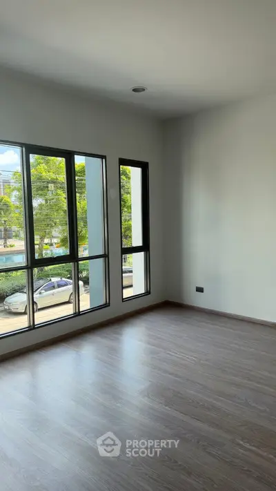 Spacious empty room with large windows and wooden flooring, offering a bright and airy atmosphere.