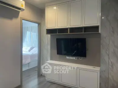 Modern apartment interior with sleek TV unit and glimpse of cozy bedroom