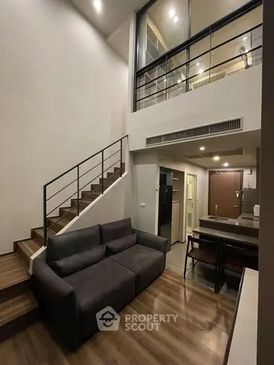 Modern loft apartment with mezzanine, sleek staircase, and cozy living area, perfect for urban living.