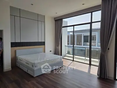 Spacious modern bedroom with large windows and balcony access, featuring elegant curtains and sleek flooring.