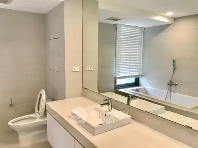 Modern bathroom with sleek fixtures and large mirror, featuring a bathtub and contemporary design.