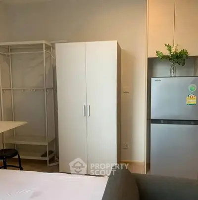 Modern studio apartment with wardrobe, fridge, and minimalist decor