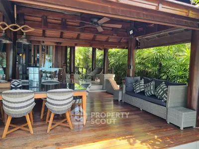 Luxurious outdoor living space with elegant wooden furniture and lush greenery, perfect for relaxation and entertaining.