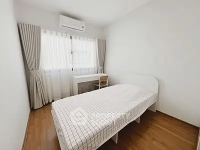 Minimalist bedroom with single bed, desk, and air conditioning in bright apartment.