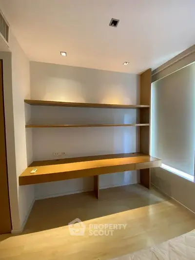 Modern study room with built-in desk and shelves, featuring sleek design and ample natural light.