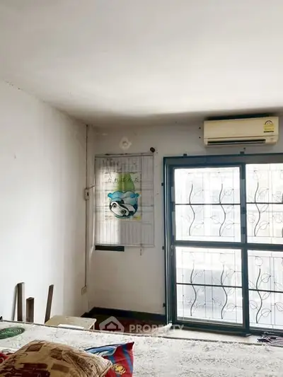 Cozy bedroom with air conditioning and large window for natural light.