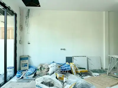 Spacious under-construction room with large windows and building materials, ideal for customization.