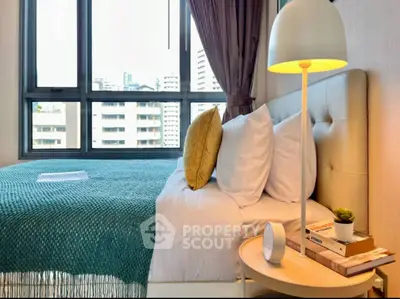 Modern bedroom with large window and stylish decor in urban apartment.