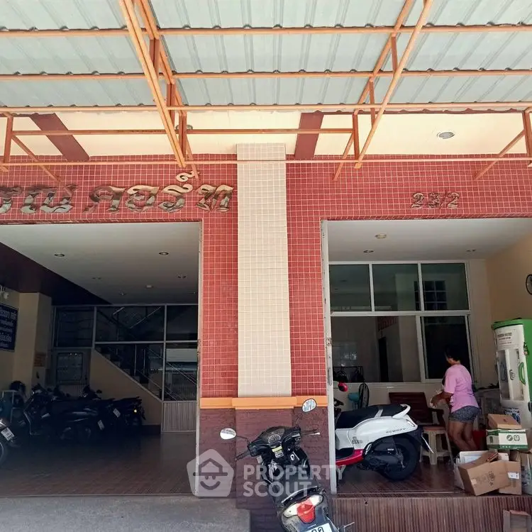 Charming building entrance with motorbike parking and tiled facade, ideal for urban living.