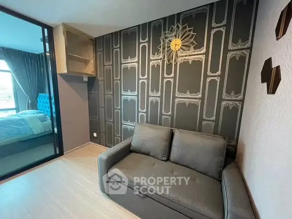 Stylish modern living room with elegant wallpaper and cozy sofa, adjacent to a chic bedroom with glass partition.