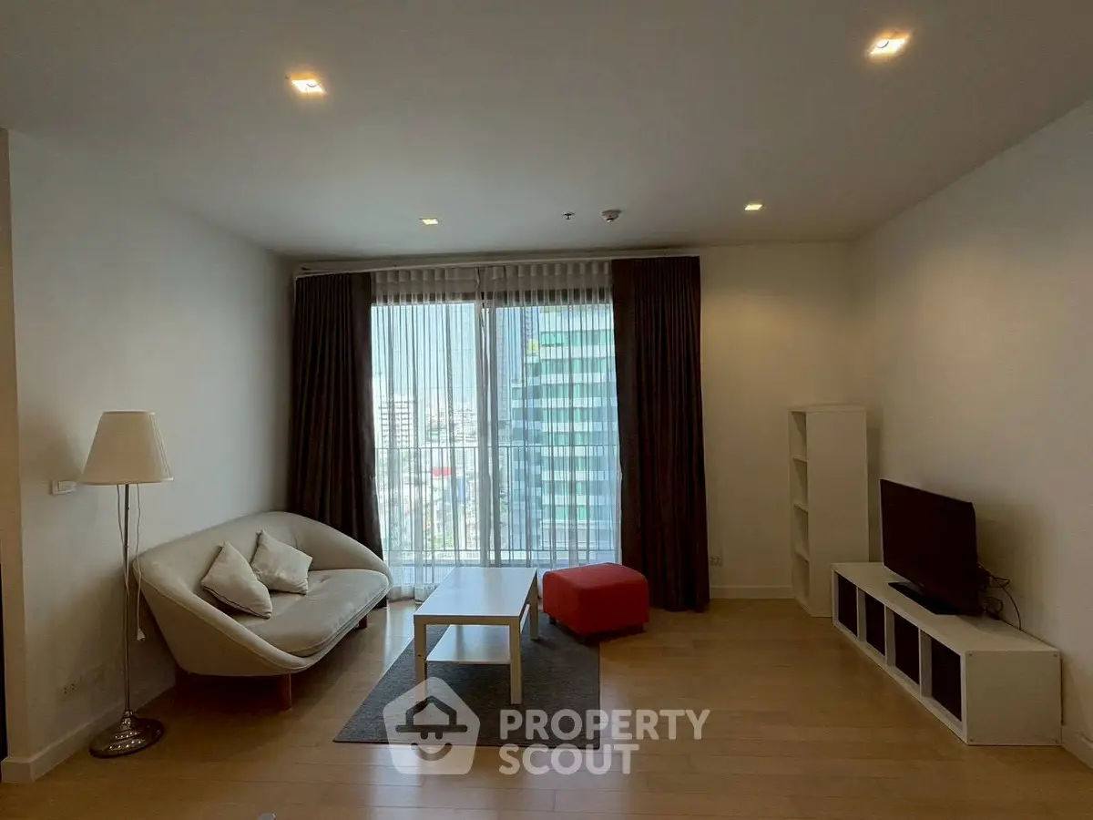 Modern living room with city view, cozy seating, and sleek entertainment unit.