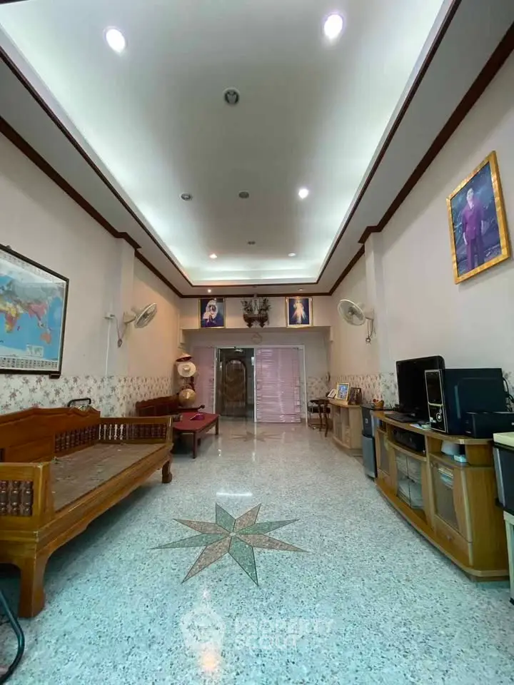 Spacious living room with high ceiling and elegant decor, featuring wooden furniture and a star-patterned floor.