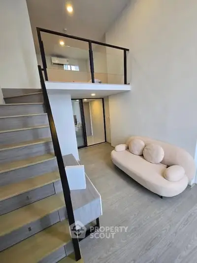 Modern loft apartment with stylish staircase and cozy seating area.