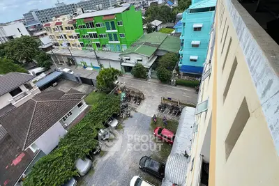 Aerial view of residential buildings with colorful facades and parking area.