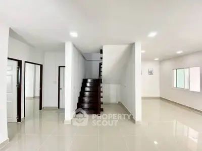 Spacious modern interior with sleek staircase and glossy tiled floors, perfect for contemporary living.