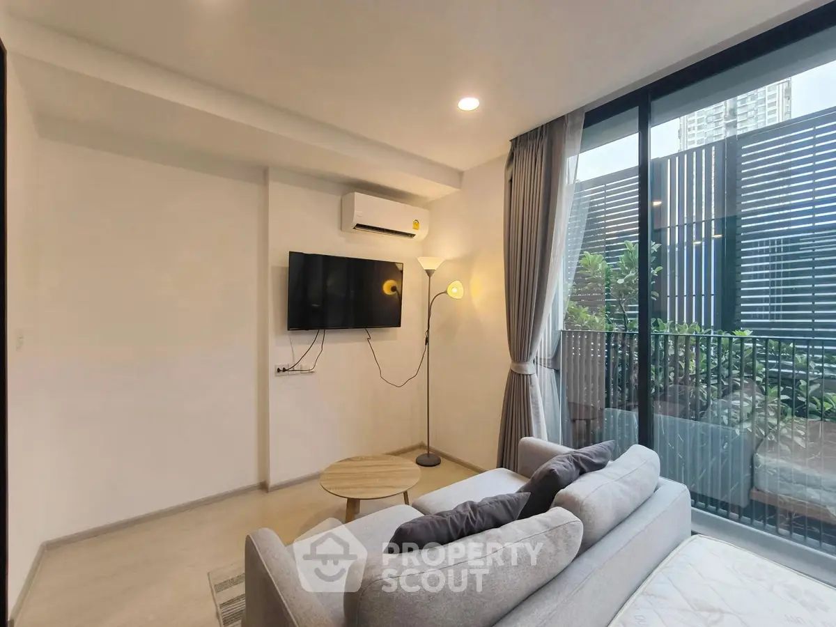 Modern living room with balcony view, featuring sleek furniture and natural light.