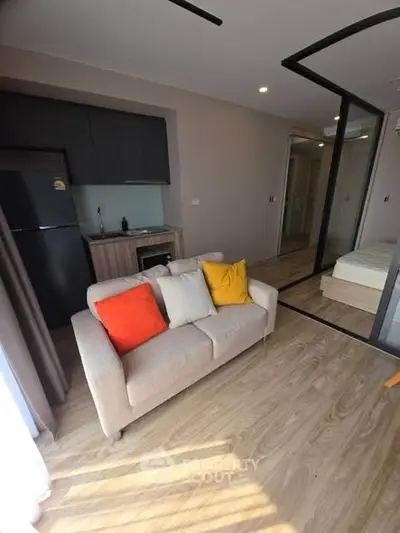 Modern studio apartment with cozy living area and compact kitchen, featuring stylish decor and natural light.