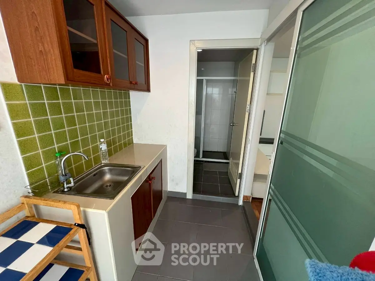 Compact kitchen with green tile backsplash and sliding glass door