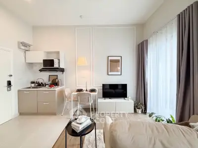 Modern open-plan living room with kitchen, cozy seating, and natural light.