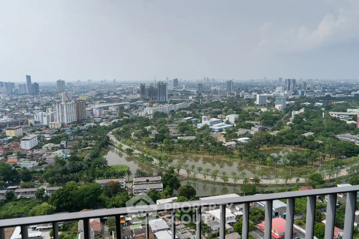 Stunning cityscape view from a high-rise balcony overlooking lush greenery and urban skyline.