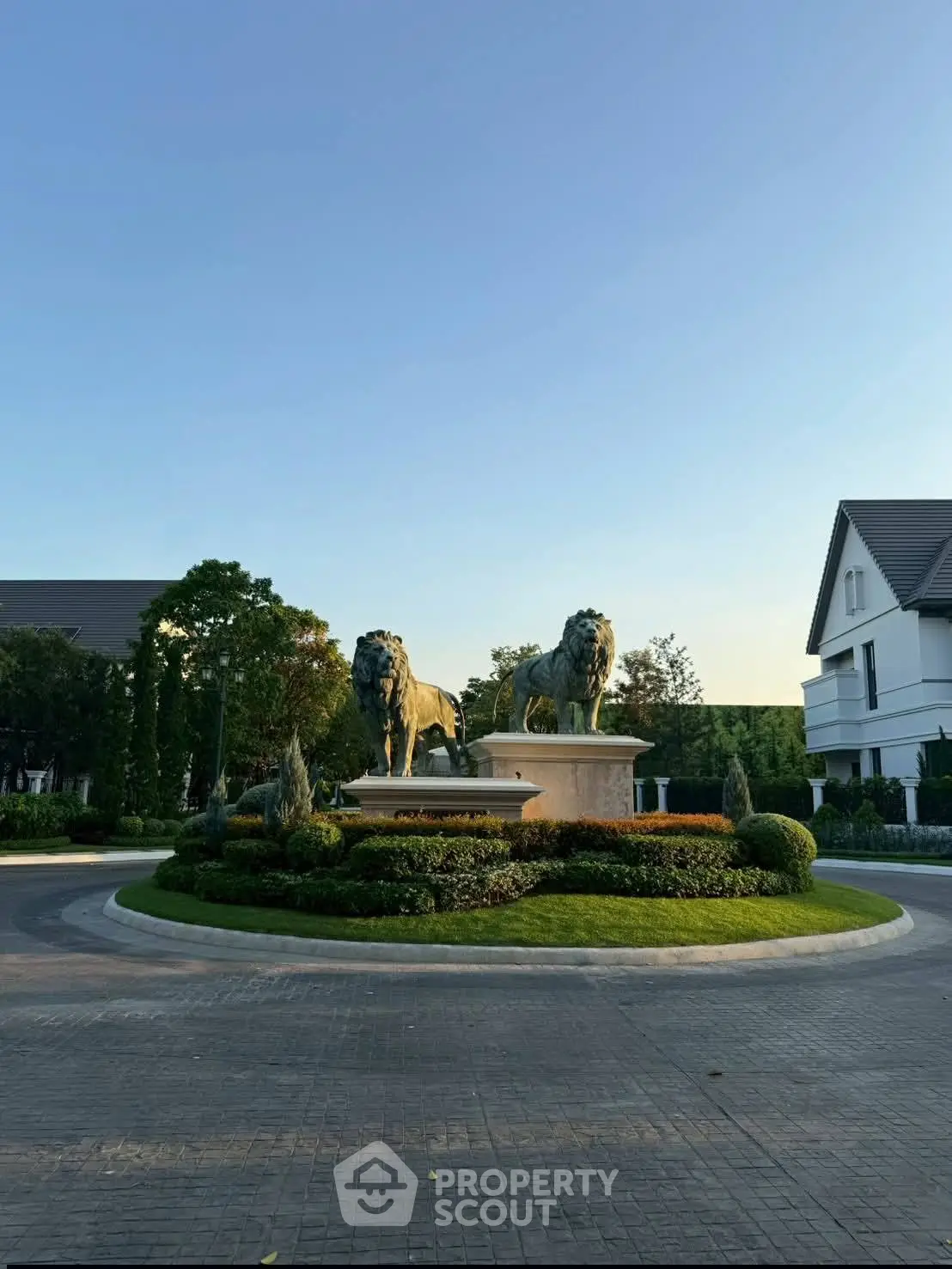 Elegant residential entrance with lion statues and lush landscaping