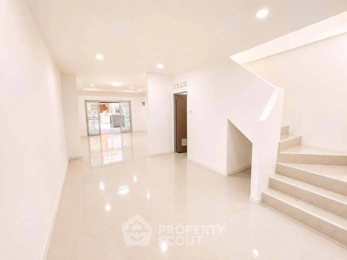 Spacious open-plan living area with staircase and bright natural lighting