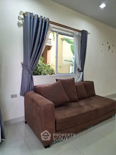 Cozy living room with brown sofa and elegant curtains, perfect for relaxation.