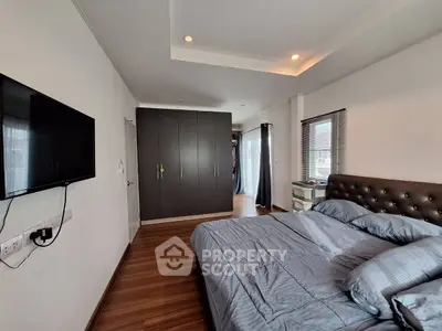 Spacious bedroom with modern decor and wall-mounted TV in luxury apartment