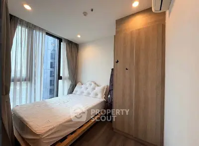 Cozy bedroom with large window and modern furnishings in urban apartment