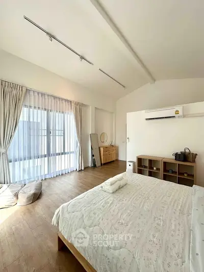 Spacious bedroom with large window and modern decor