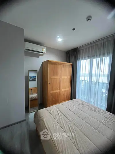 Cozy bedroom with wooden wardrobe and large window offering natural light