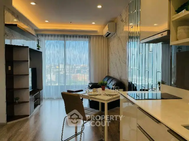 Modern living room with open kitchen and city view, featuring sleek furniture and elegant decor.