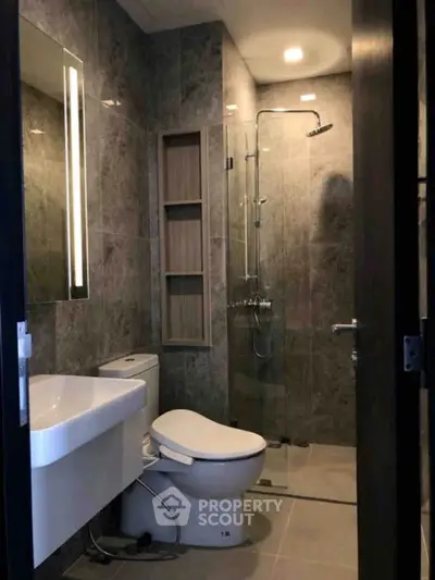 Modern bathroom with sleek design, featuring a glass shower enclosure and contemporary fixtures.