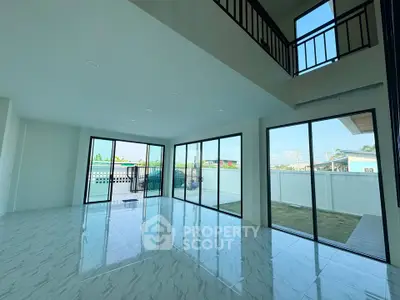 Spacious modern living room with large windows and high ceilings, offering abundant natural light and garden views.