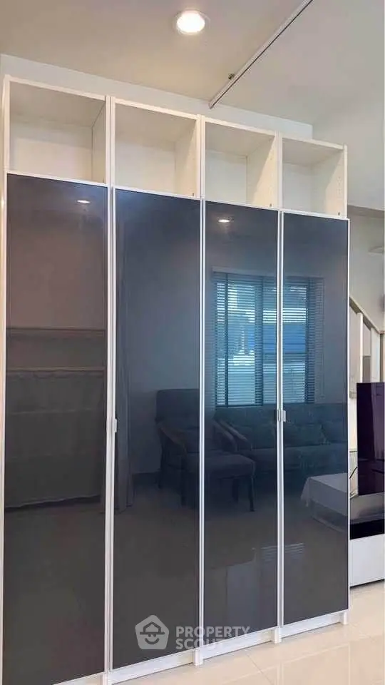 Modern living room with sleek glass cabinets and cozy seating area.