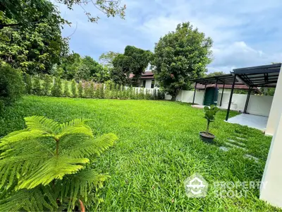 Spacious green garden with lush lawn and covered patio in serene residential area.