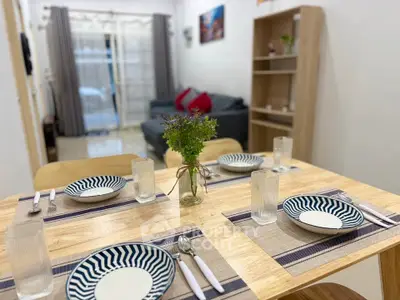 Modern dining area with stylish table setting and cozy living room in background.