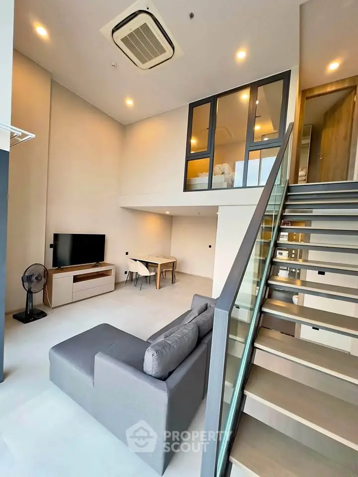 Modern loft apartment with high ceilings, stylish staircase, and cozy living area.