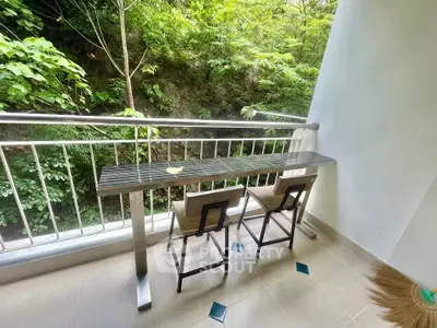 Charming balcony with lush green view and stylish seating, perfect for relaxation.