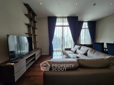 Spacious living room with modern sofa and large TV, featuring floor-to-ceiling windows with city view.