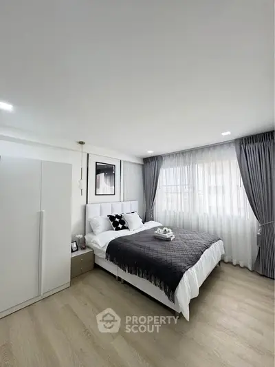 Modern bedroom with elegant decor and natural light, featuring a cozy bed and stylish curtains.