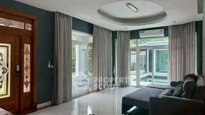 Spacious living room with large windows and pool view, featuring modern decor and natural light.