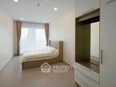 Spacious modern bedroom with large window and built-in wardrobe