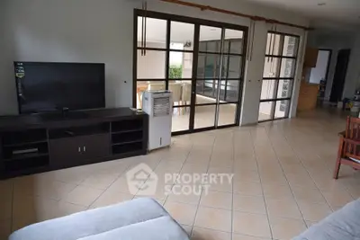 Spacious living room with large windows and tiled flooring, opening to a balcony.