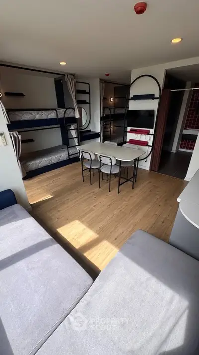Modern living room with bunk beds and dining area, featuring stylish decor and natural light.