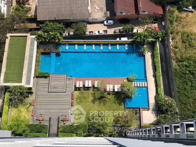 Stunning aerial view of luxurious residential pool area with lush greenery and sun loungers.