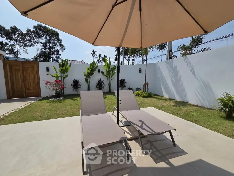 Luxurious outdoor garden with sun loungers and umbrella, perfect for relaxation and leisure.